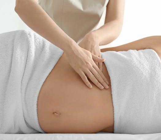 Une thérapeute pratique un massage du ventre à une femme enceinte